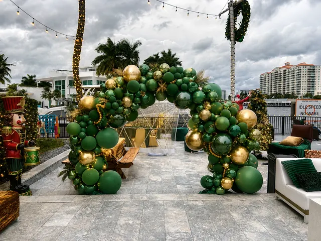 Green and gold balloon arch at a waterfront holiday event